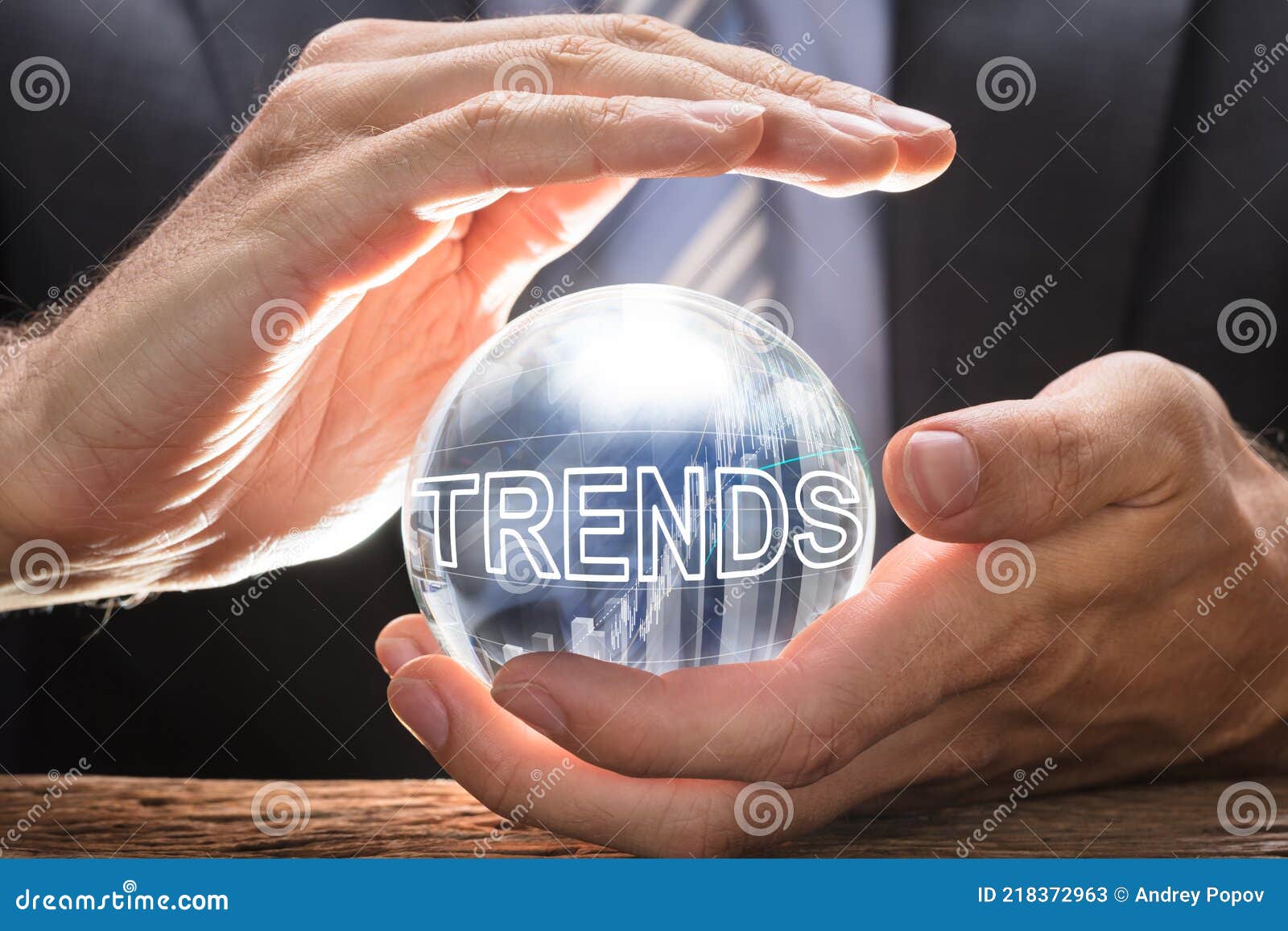 businessman covering crystal ball with trends text and graphs