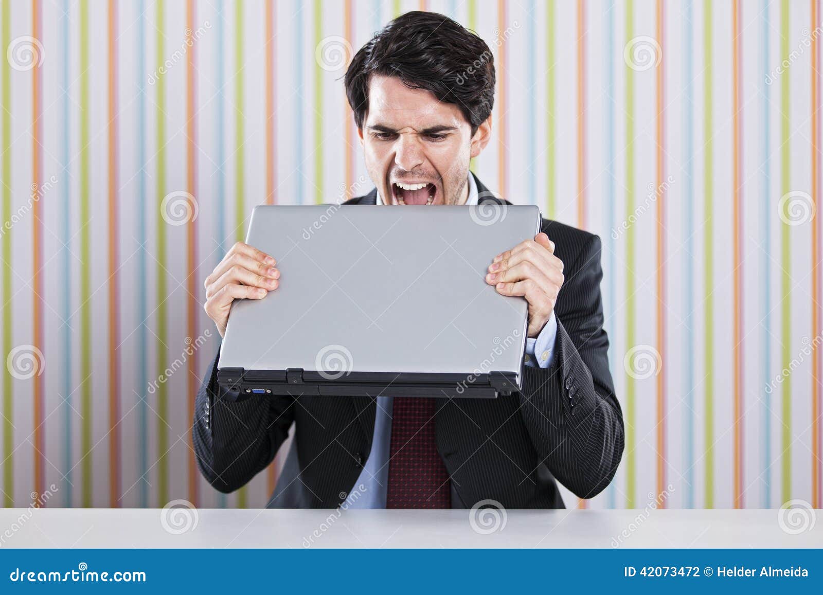 Businessman eating laptop. Crazy businessman eating his laptop