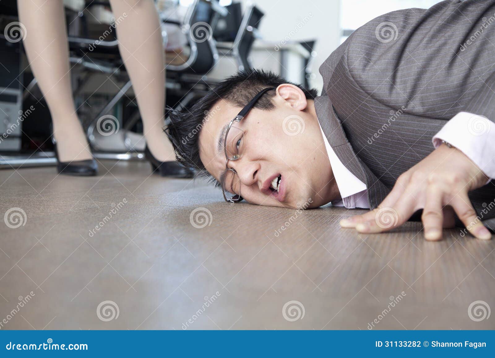 Businessman With Face On The Floor Coworker Standing By Him Stock