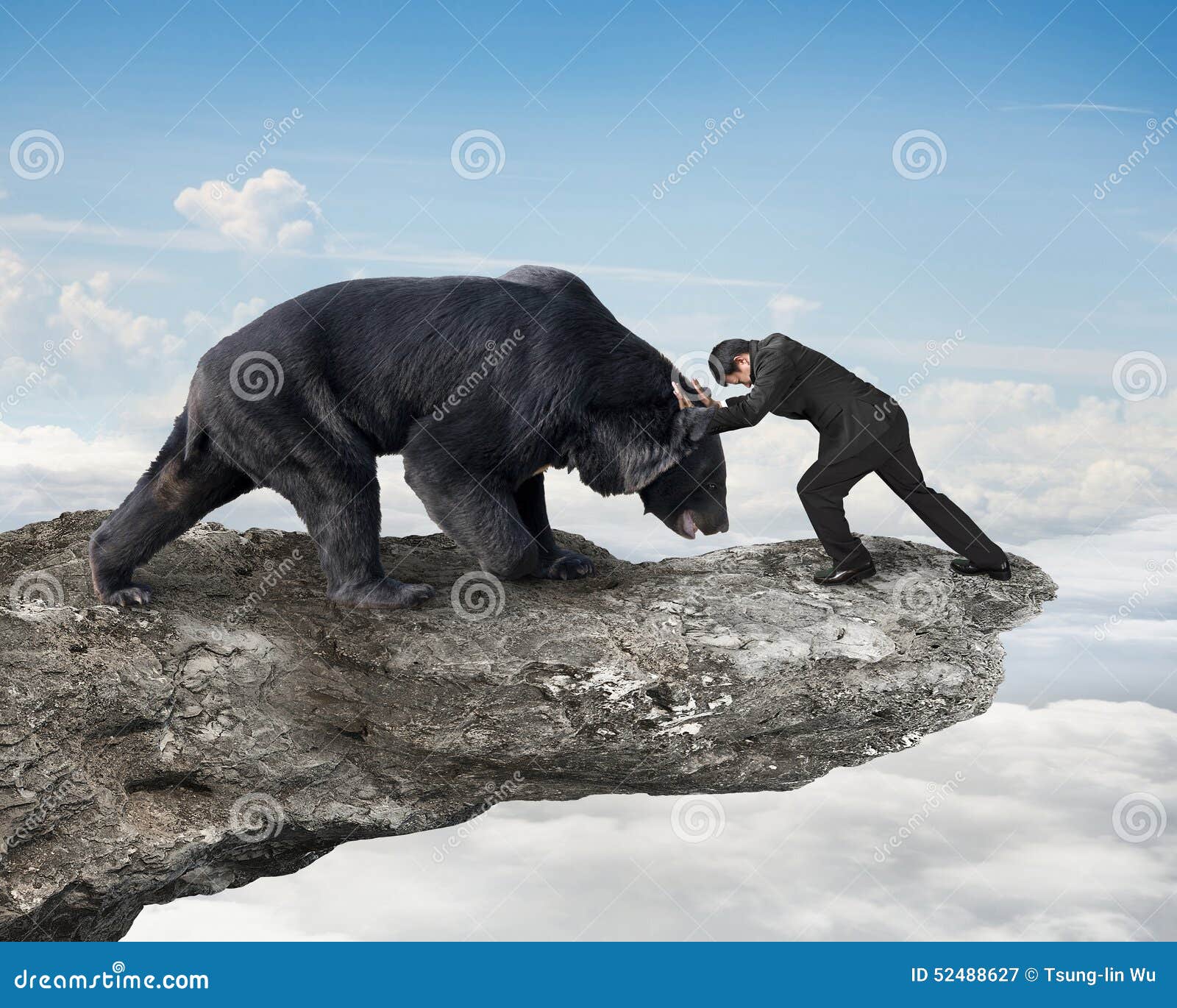 businessman fighting against black bear on cliff with sky clouds