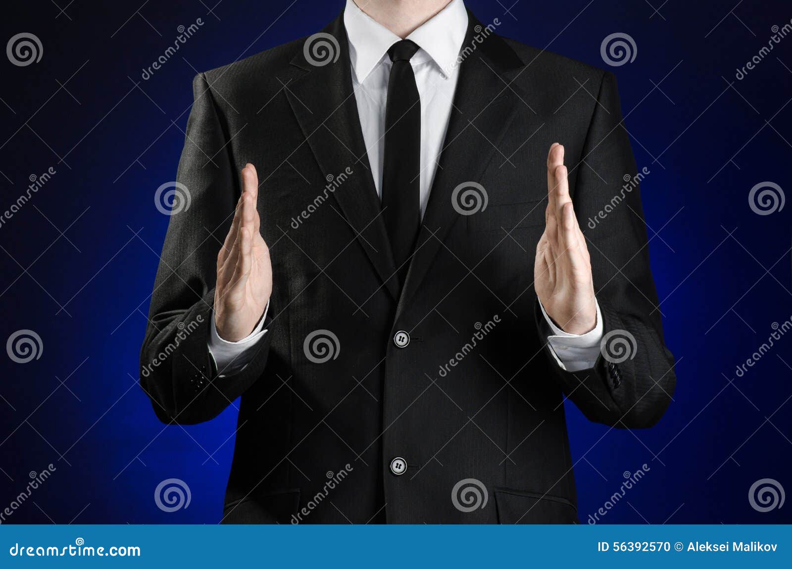 businessman and gesture topic: a man in a black suit and white shirt showing gestures with hands on a dark blue background in stud