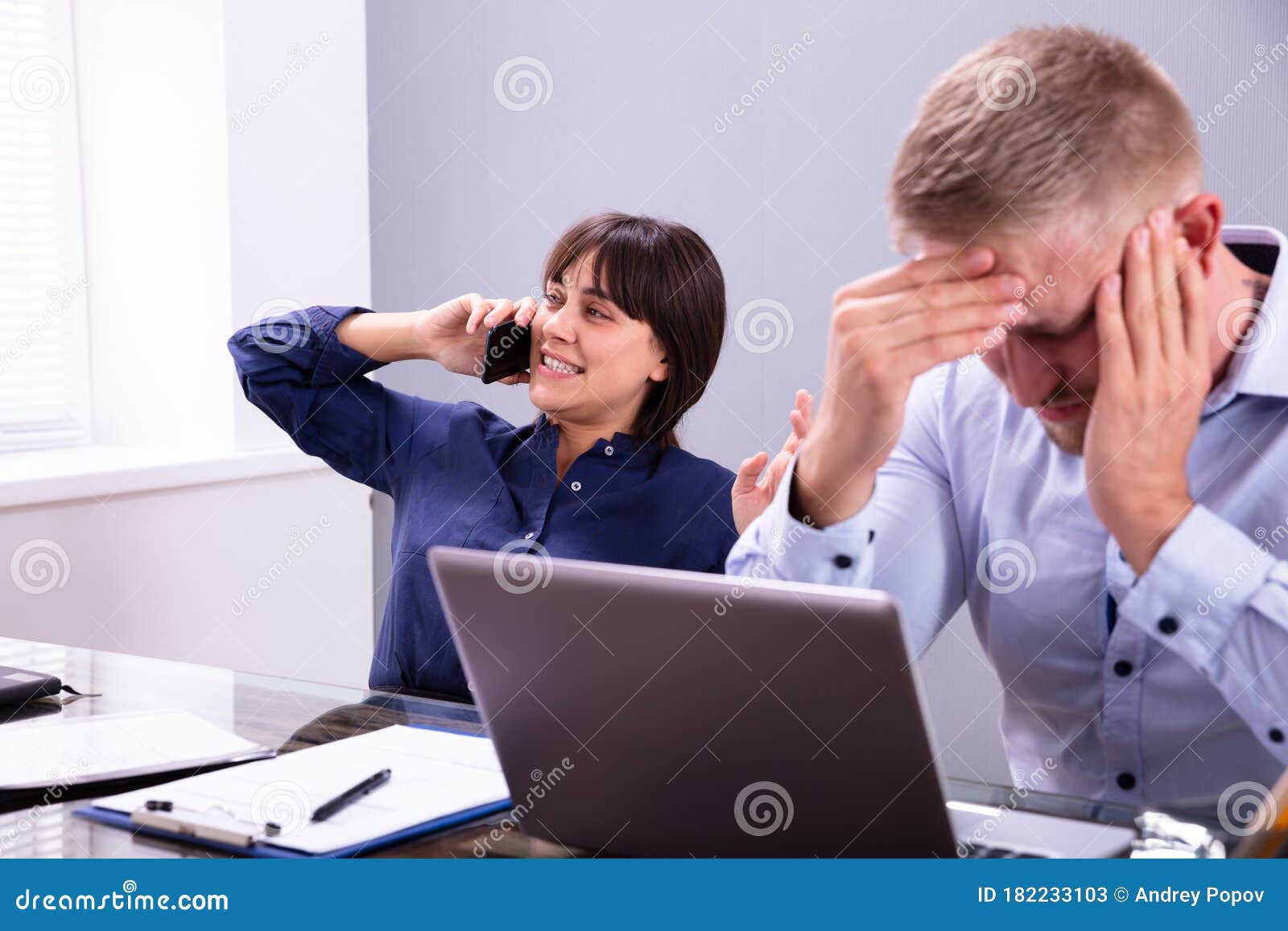businessman getting irritated with colleague talking on phone