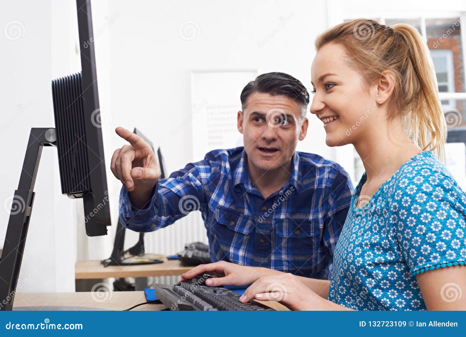 businessman giving computer training to female trainee in offic