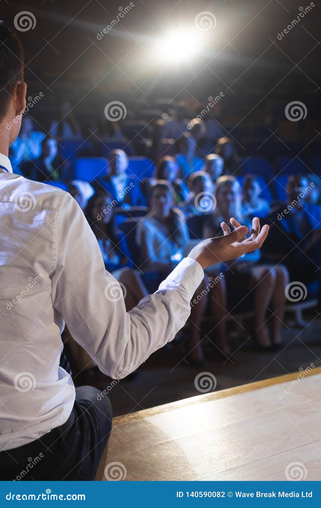Businessman Giving Presentation In Front Of Audience In Auditorium
