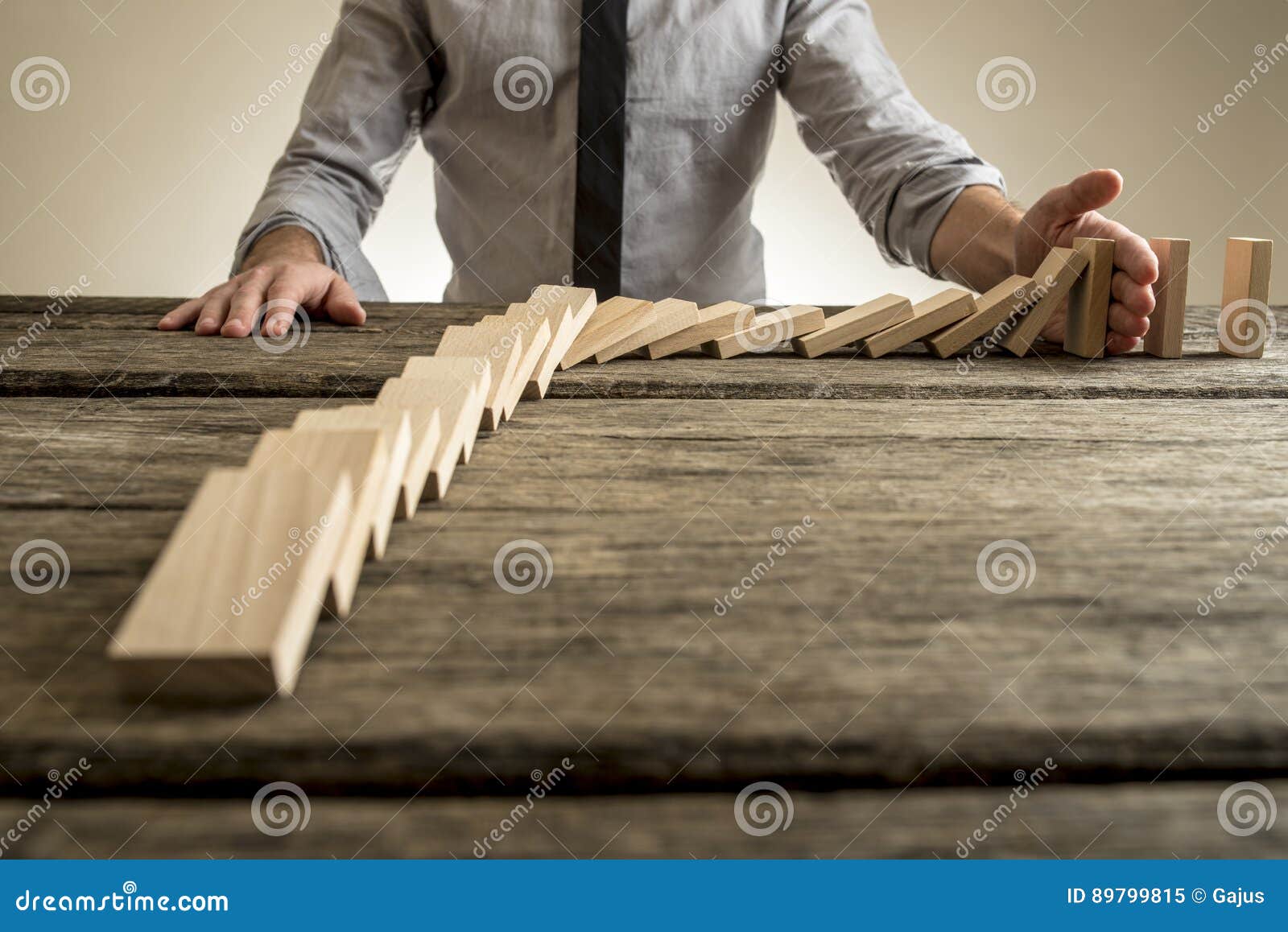 businessman hand stopping domino effect