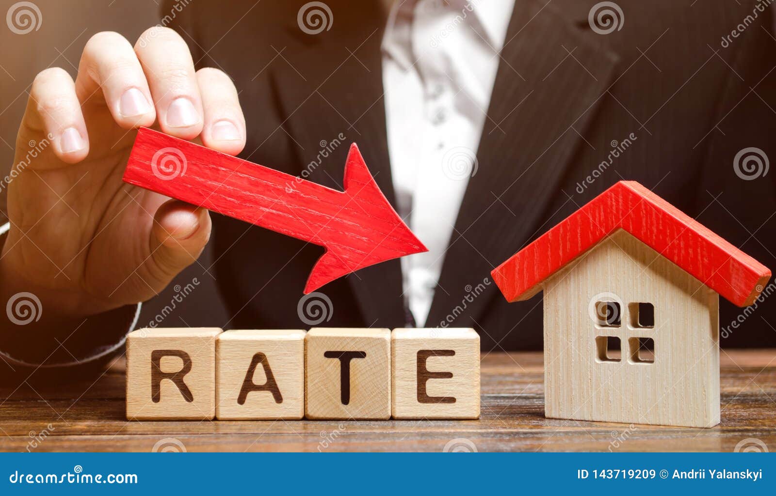 businessman holding the down arrow on wooden blocks with the word rate and house. low interest in mortgages. reducing interest