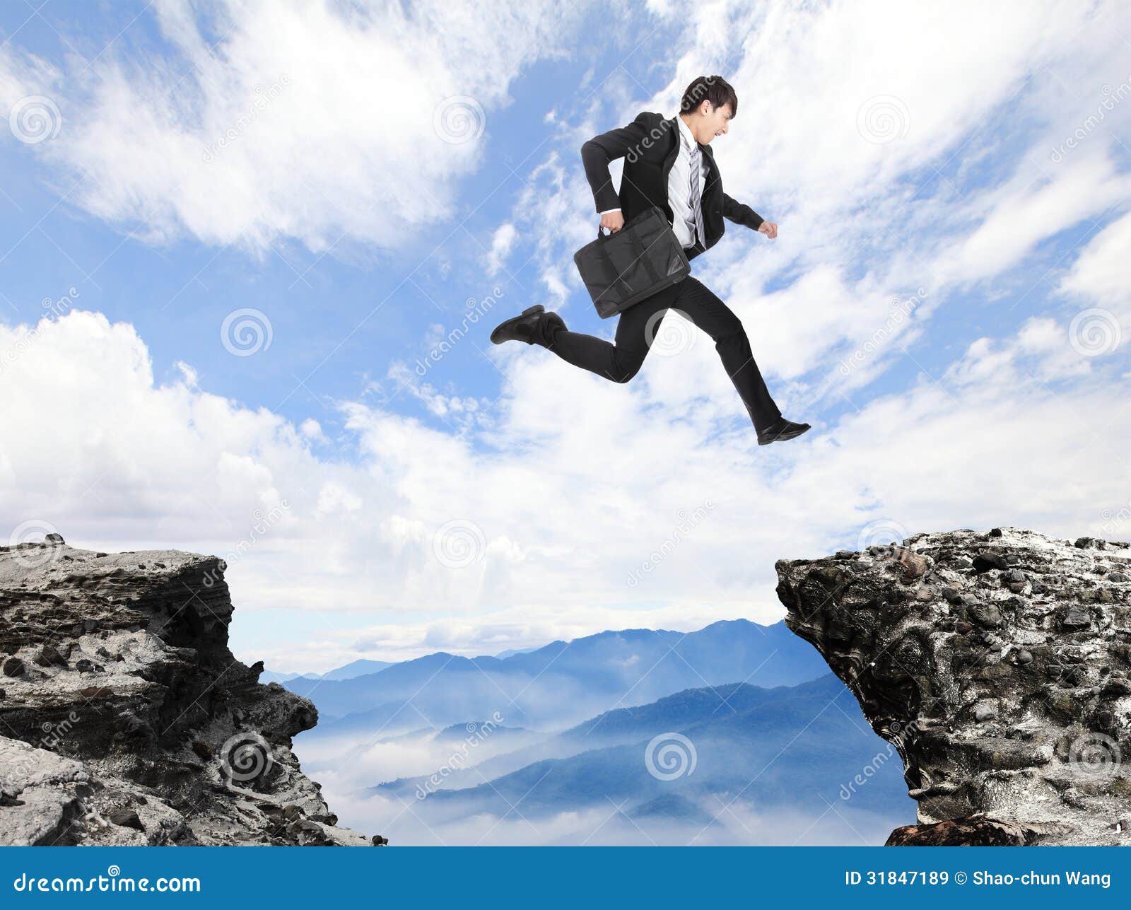 businessman jumping over danger precipice