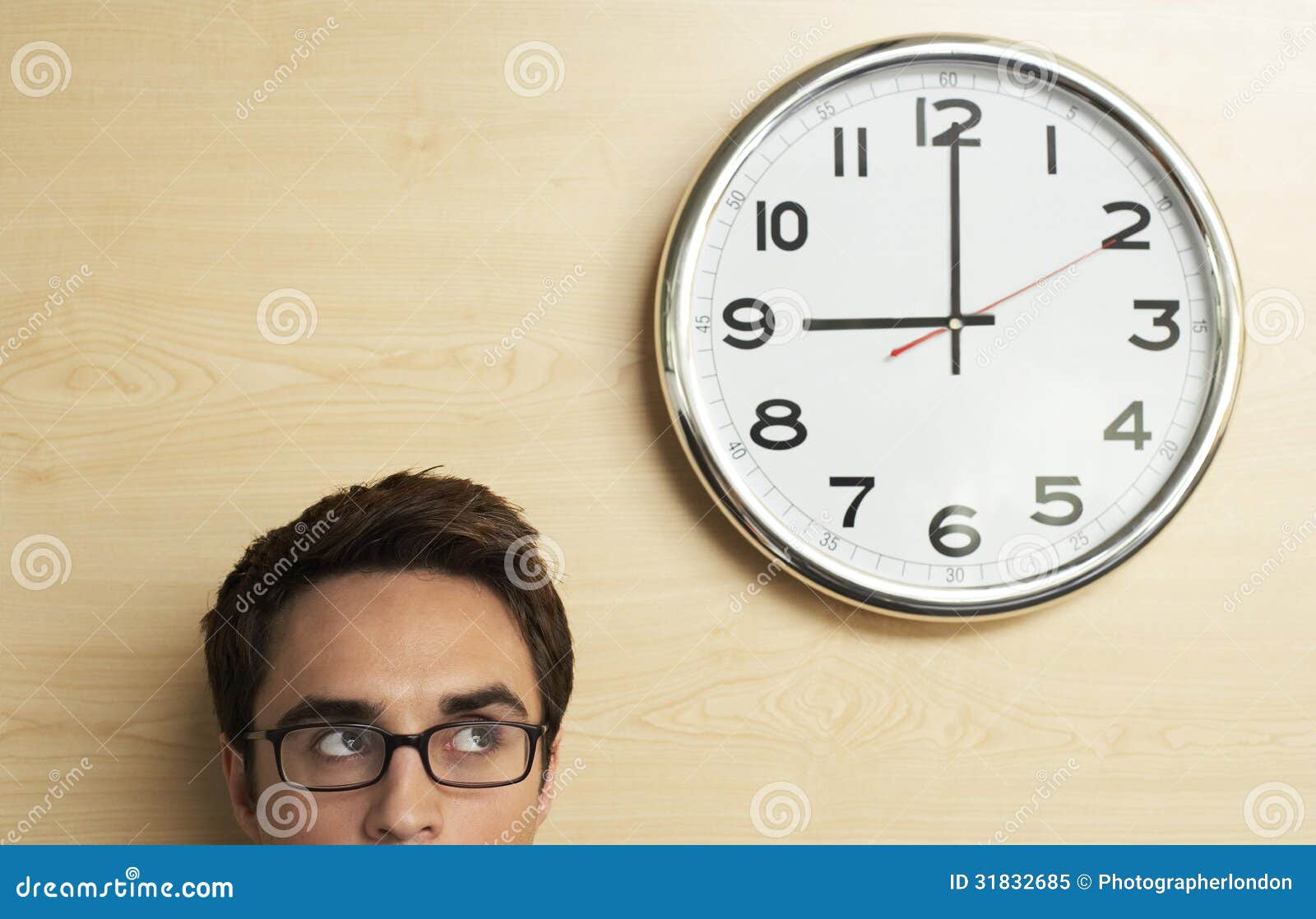 businessman looking at clock on wooden wall in office