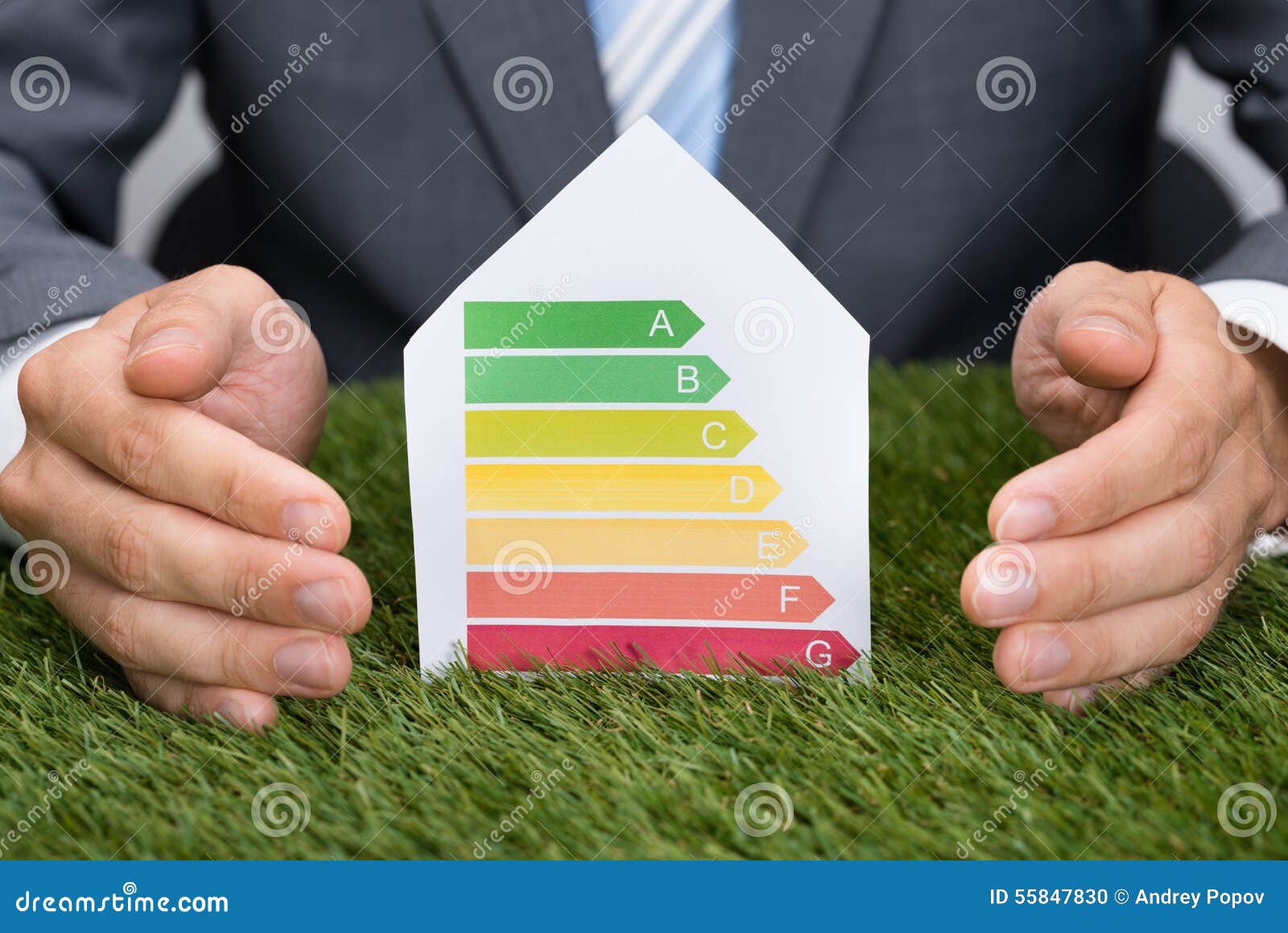 businessman protecting energy consumption label on grass