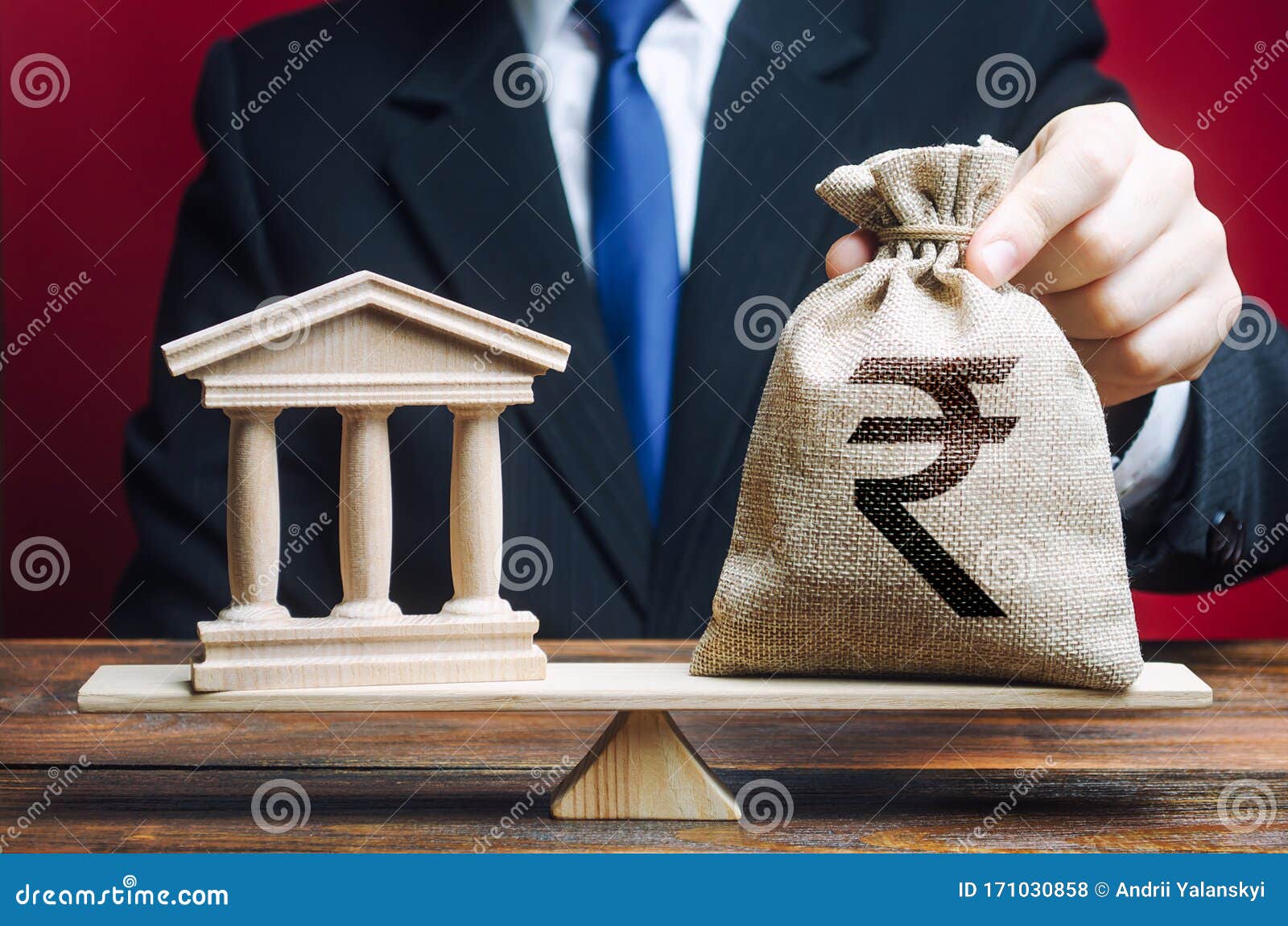 businessman puts a indian rupee money bag on scales opposite to government building, bank, university. lobbying interests. taxes