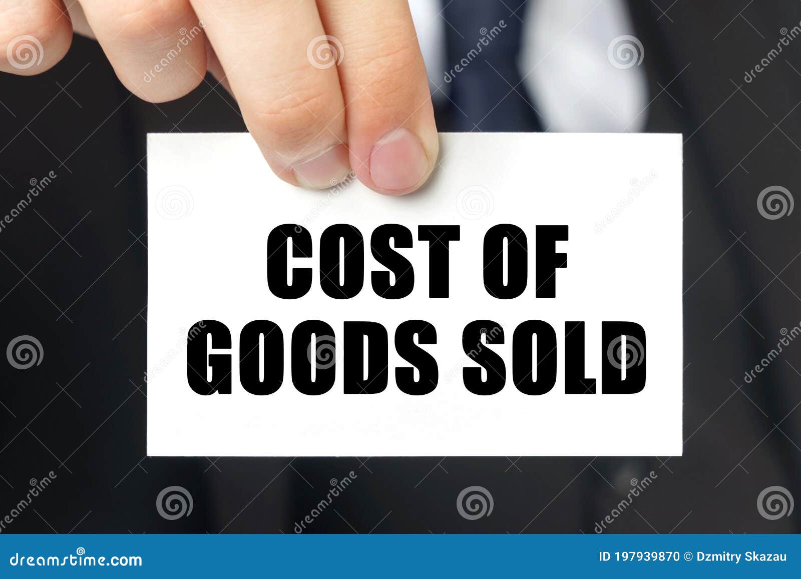 businessman shows a card with the text - cost of goods sold