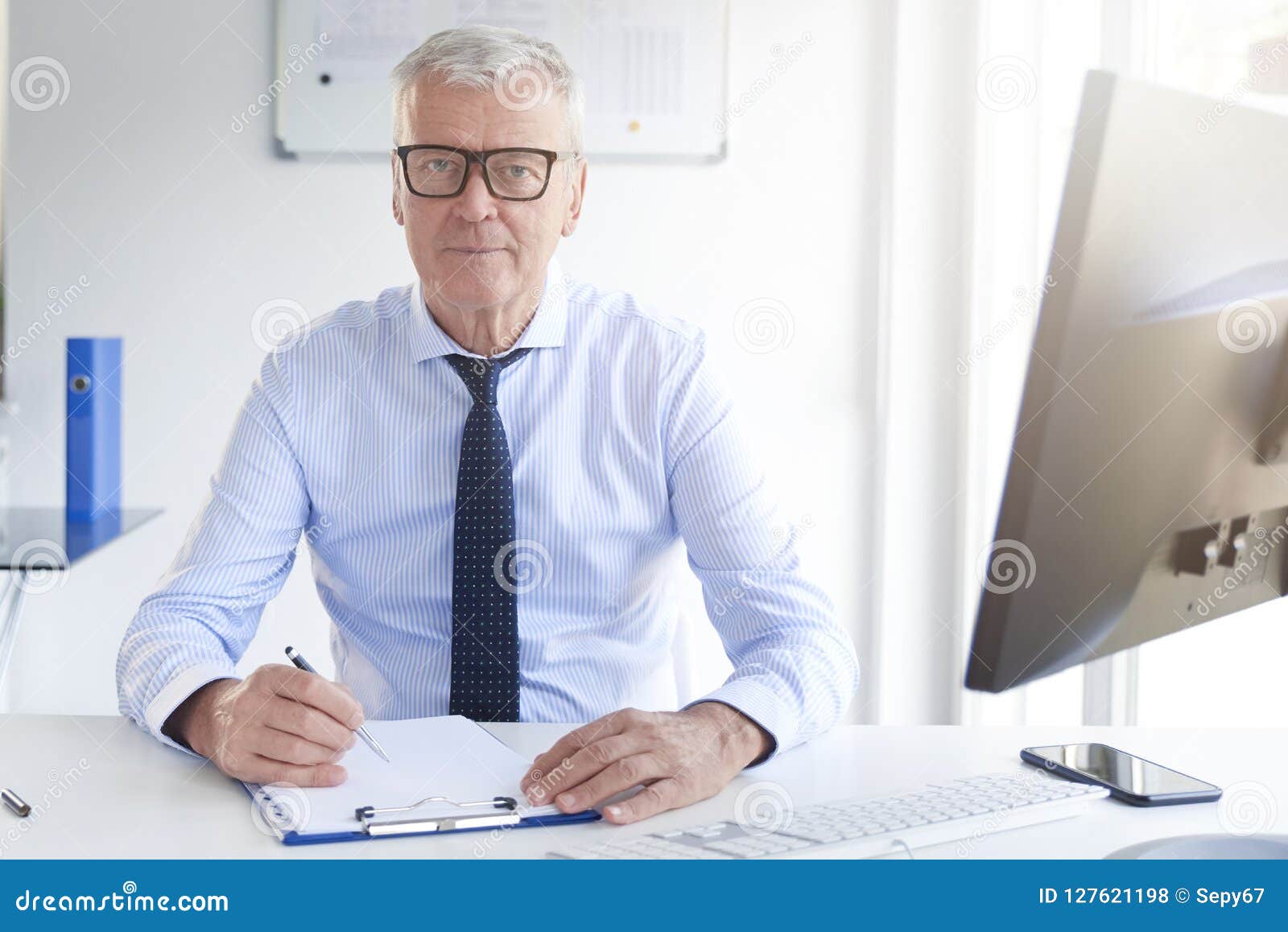 Businessman Sitting At Office Desk And Making Notes Stock Photo
