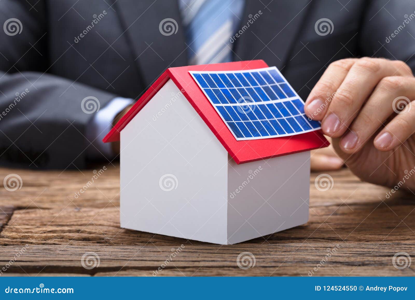 businessman sticking solar panel on model home