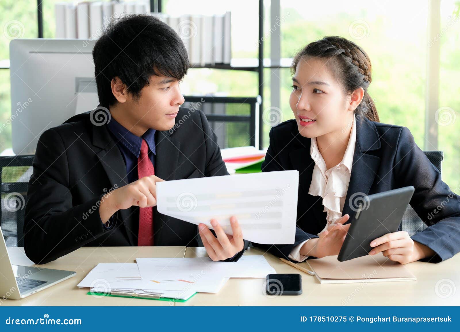businessman is talking with his collegue and point to paper chart in the modern office