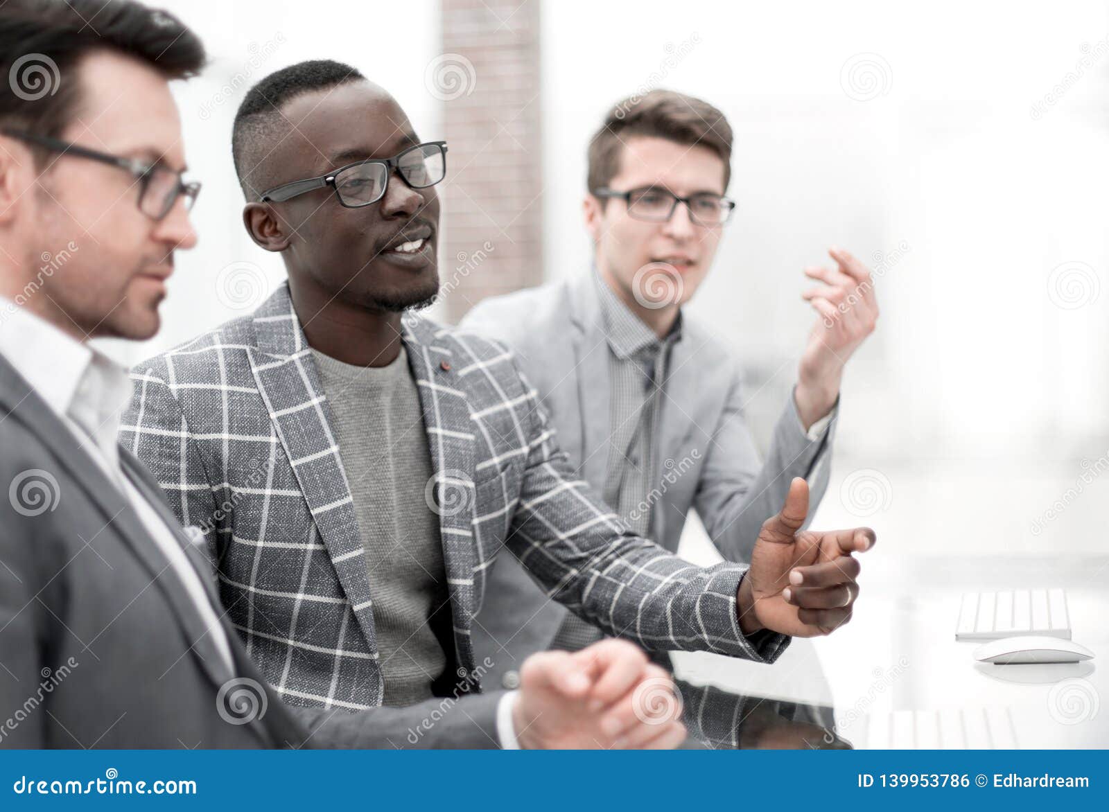 Businessman Talking To Employees and Sitting Behind a Desk Stock Photo ...