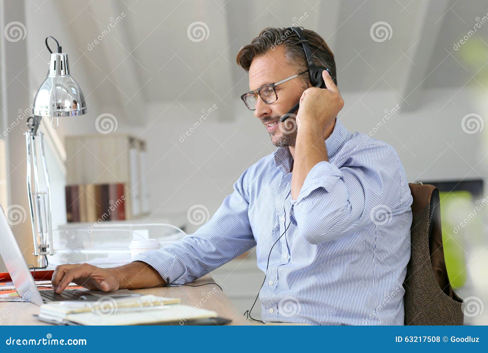 businessman teleworking with headset on laptop