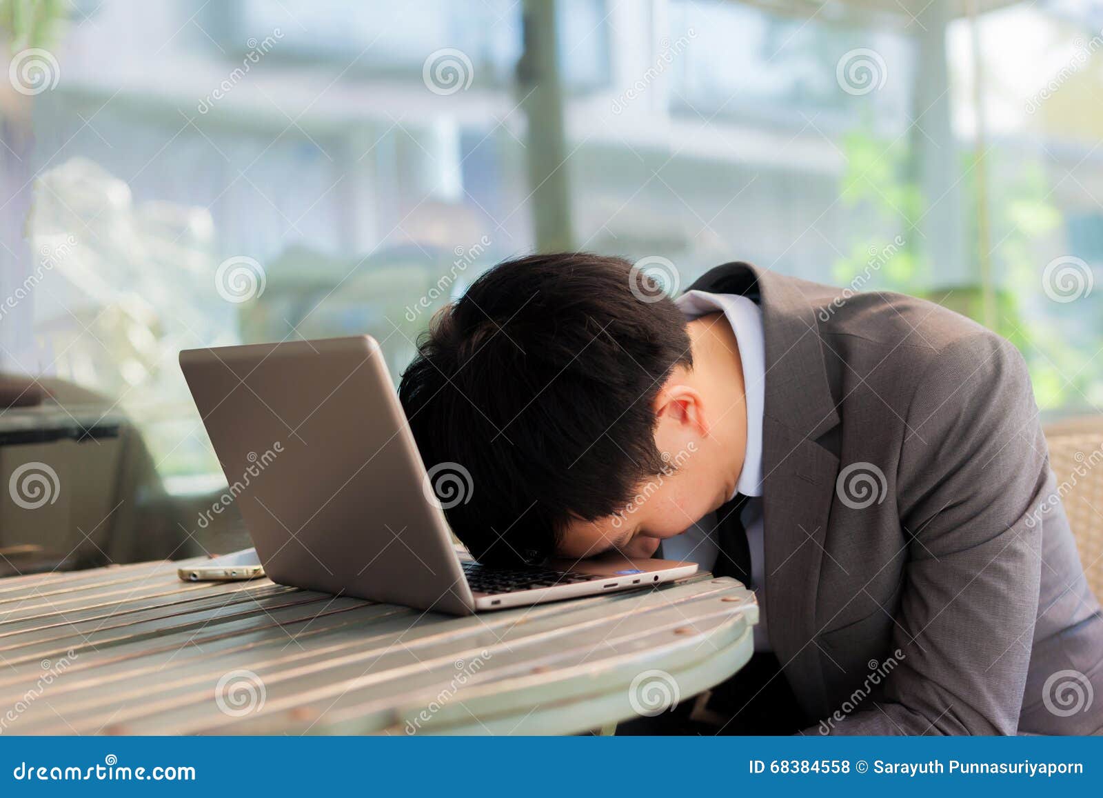 businessman tiring and sleeping on his laptop in outdoor scene