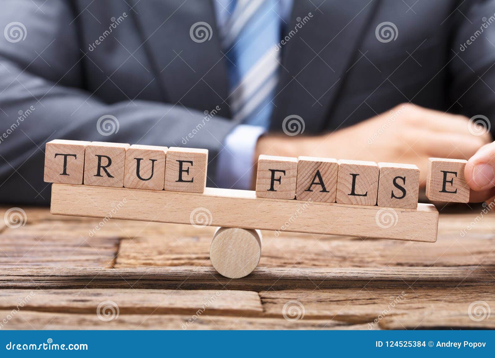 businessman with true and false wooden blocks on seesaw