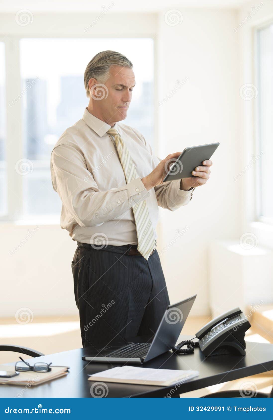 Businessman Using Digital Tablet while Standing by Desk Stock Image