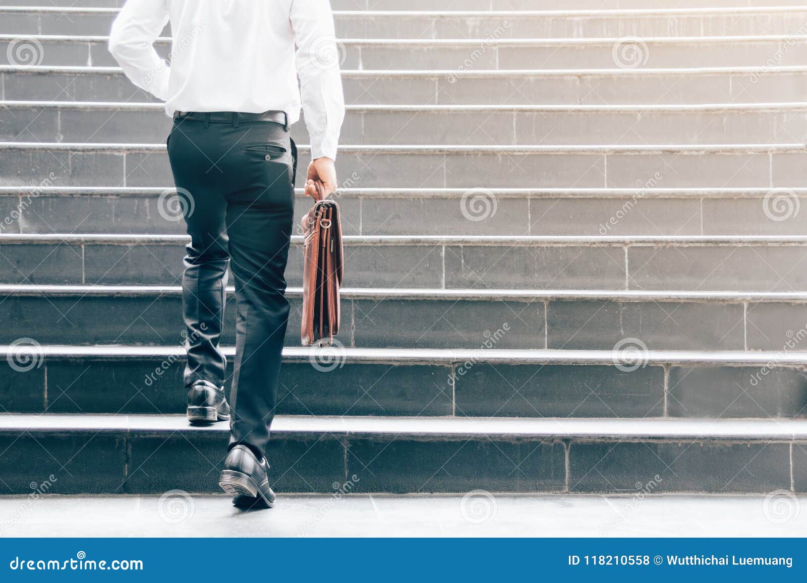 businessman walking up on stairs and holding briefcase.