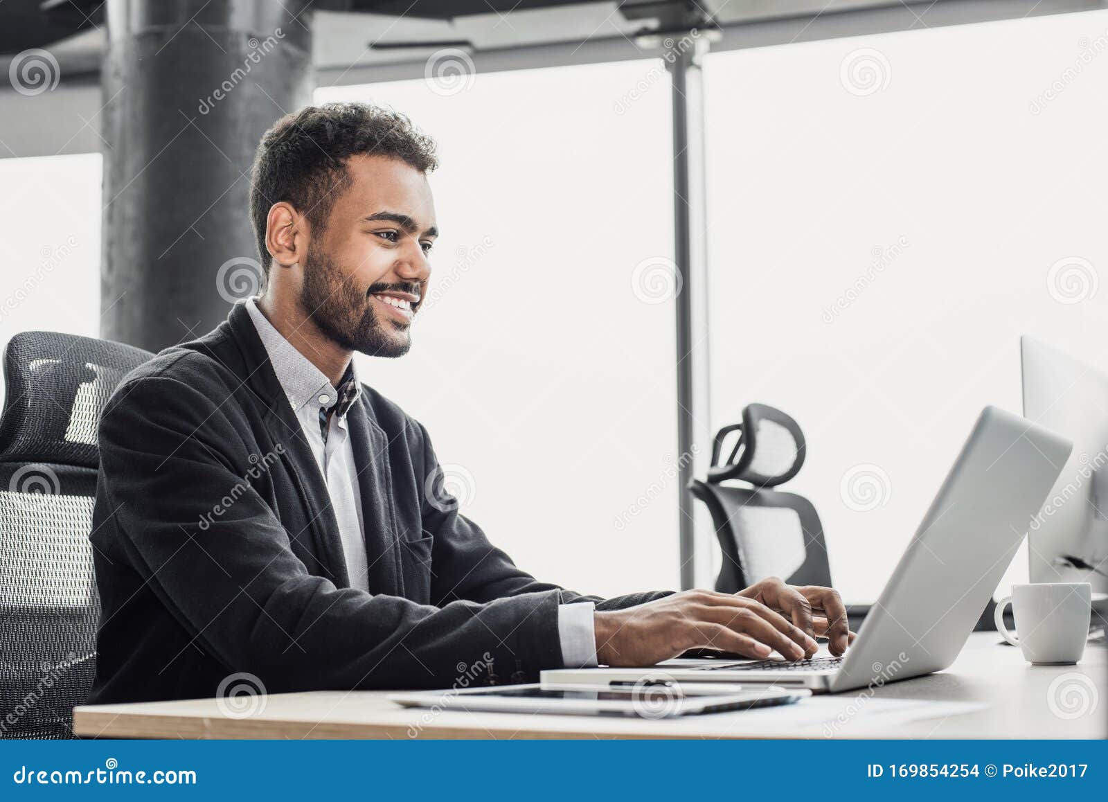 businessman working on computer. young smiling man using laptop in the office. internet marketing, finance, business concept