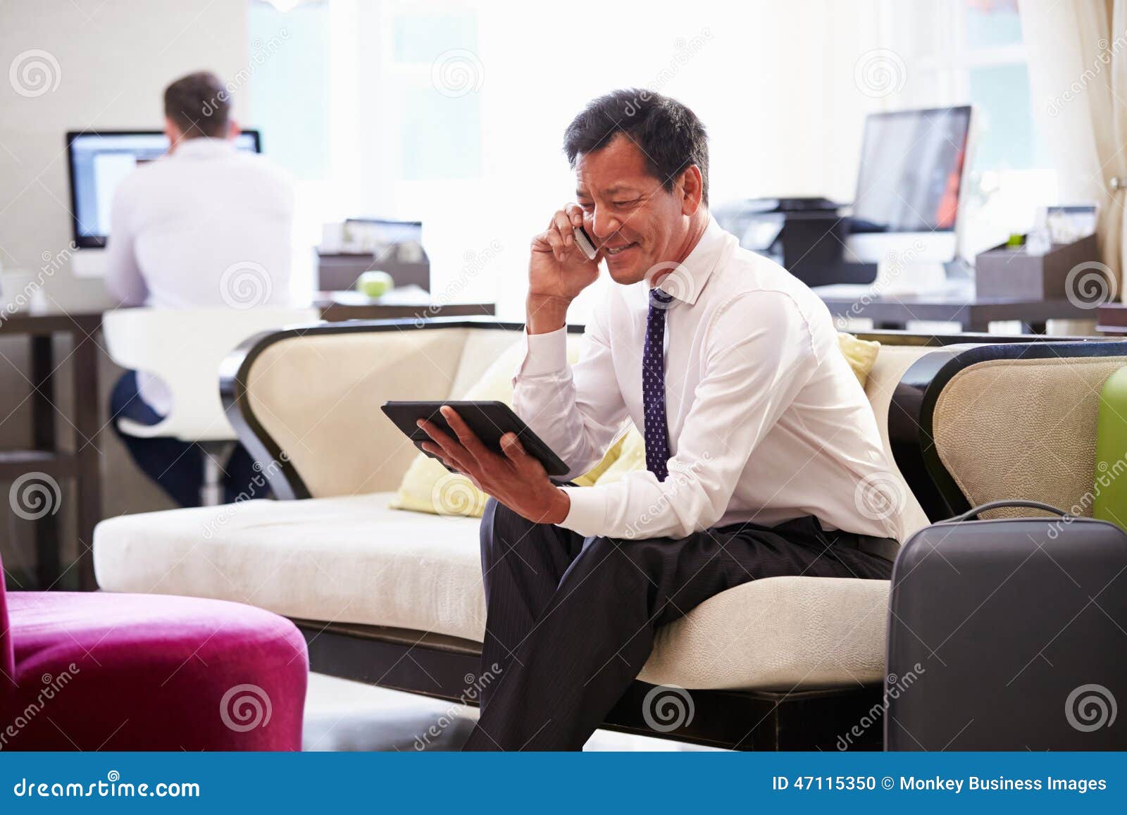Businessman Working on Digital Tablet in Hotel Lobby Stock Photo