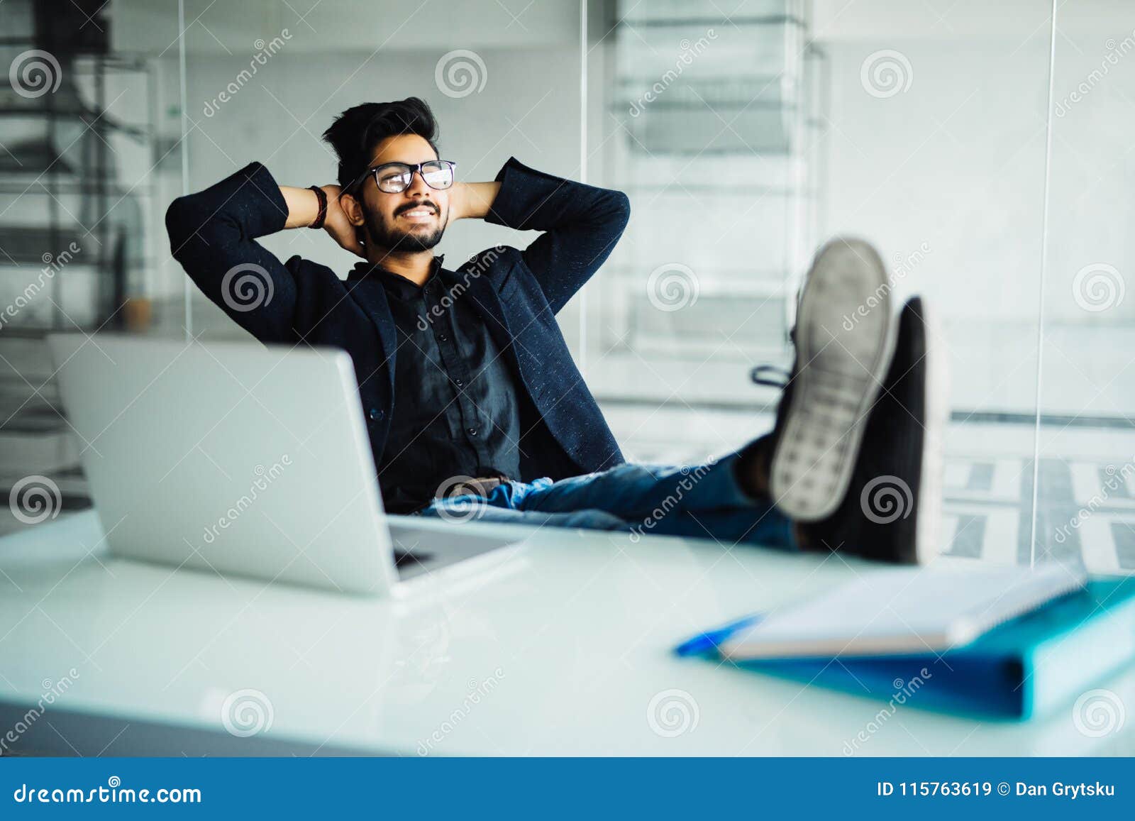 Businessman sitting in office with feet up on desk - Stock Photo