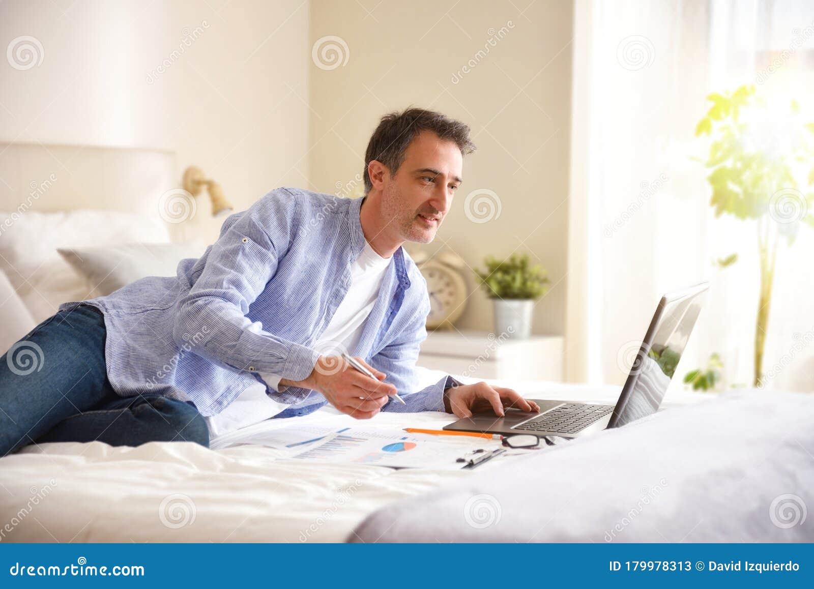 businessman working with a laptop smiling lying on a bed