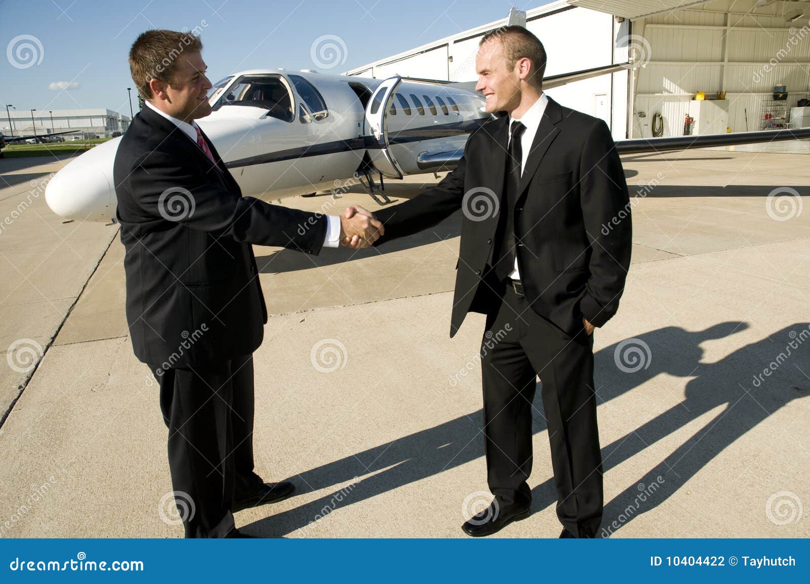 businessmen shaking hands in front of corporate je