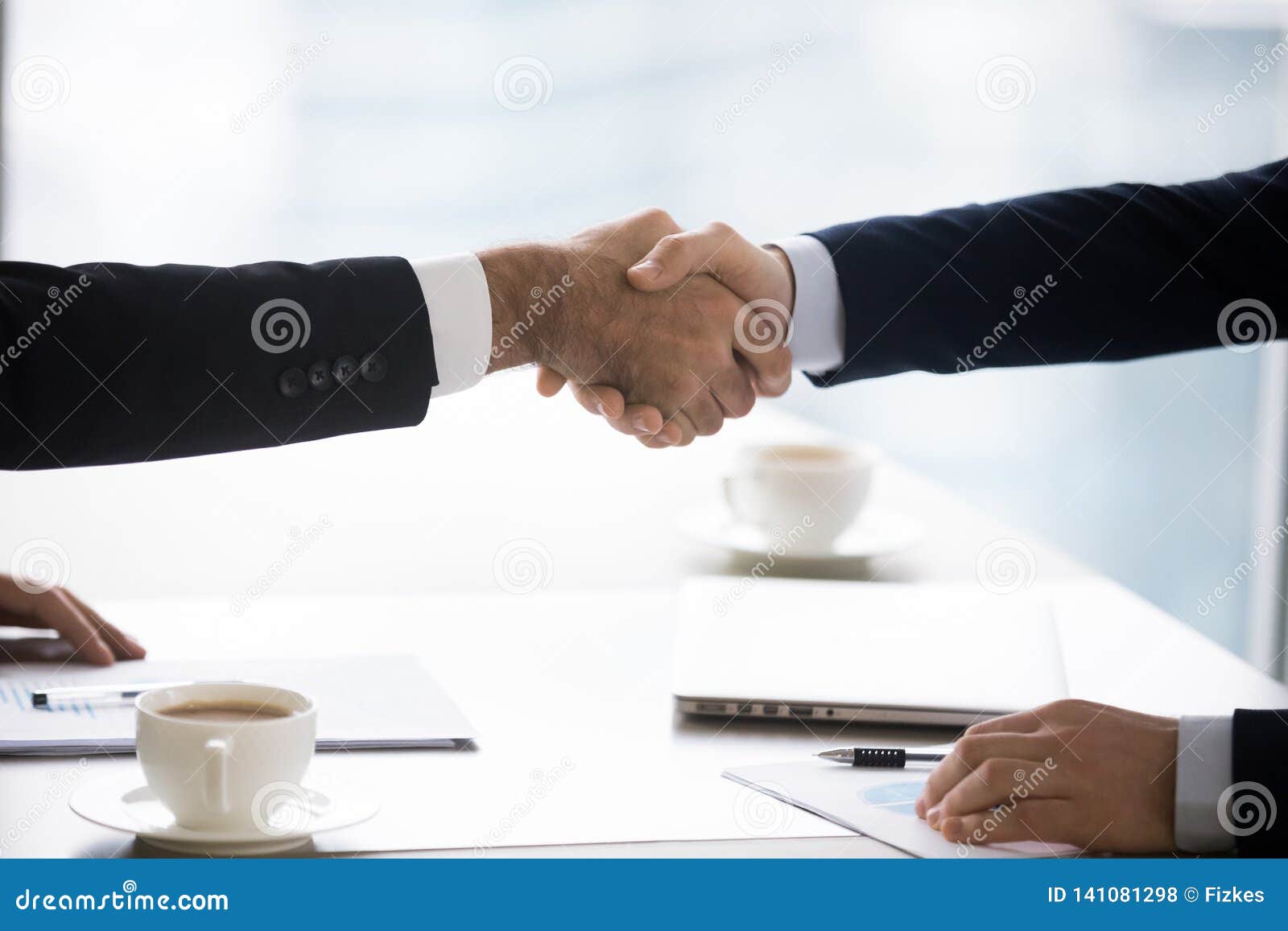 businessmen in suits handshake after successful negotiation closing deal, closeup