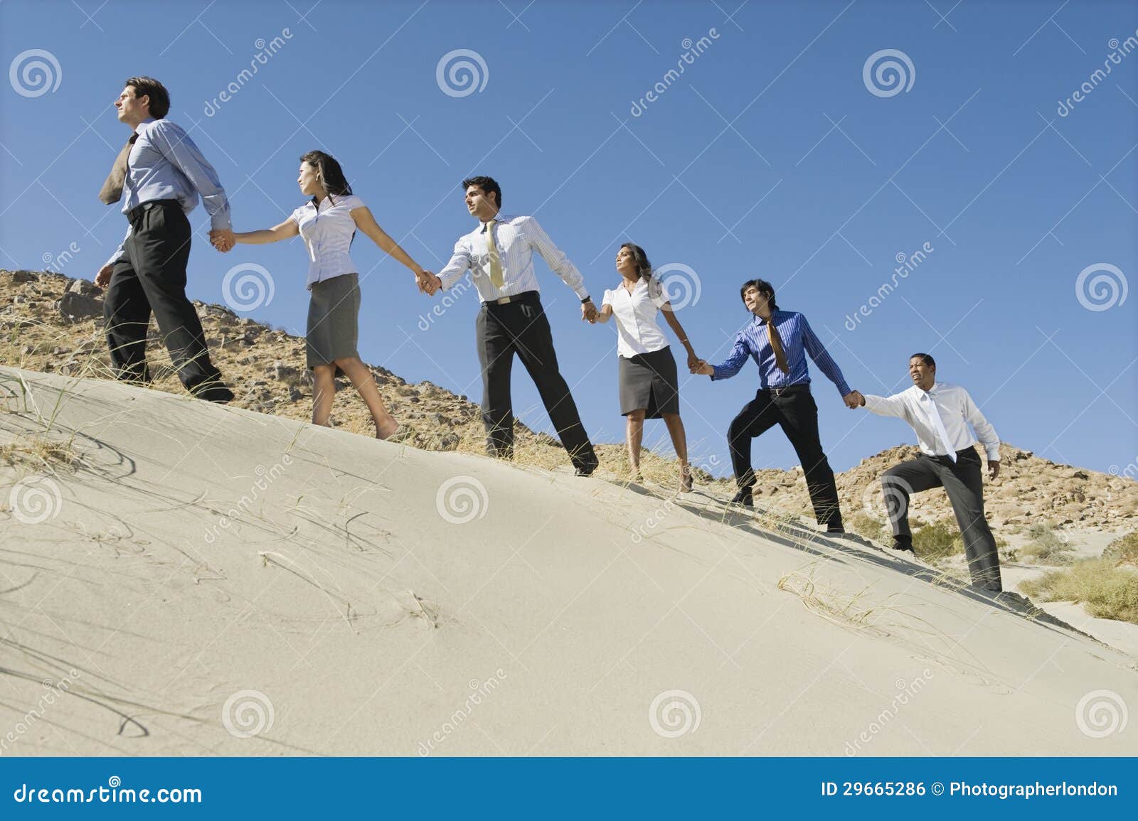 businesspeople holding hands and walking uphill