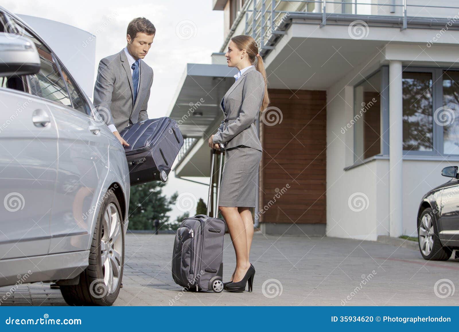 Businesspeople Unloading Luggage from Car Outside Hotel Stock Photo