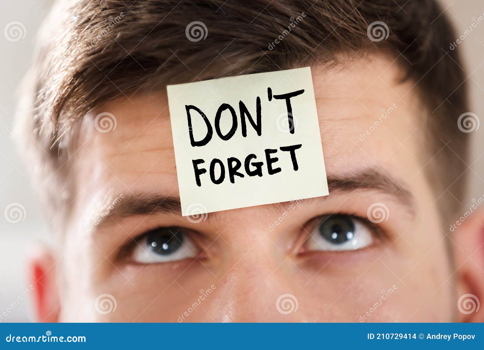 sticky note with don`t forget text stuck on man`s forehead