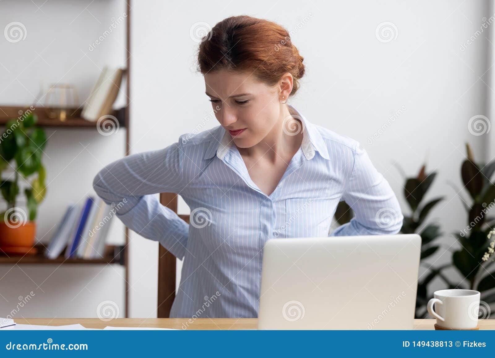 Businesswoman Feeling Back Pain Sitting On Chair Touching Aching