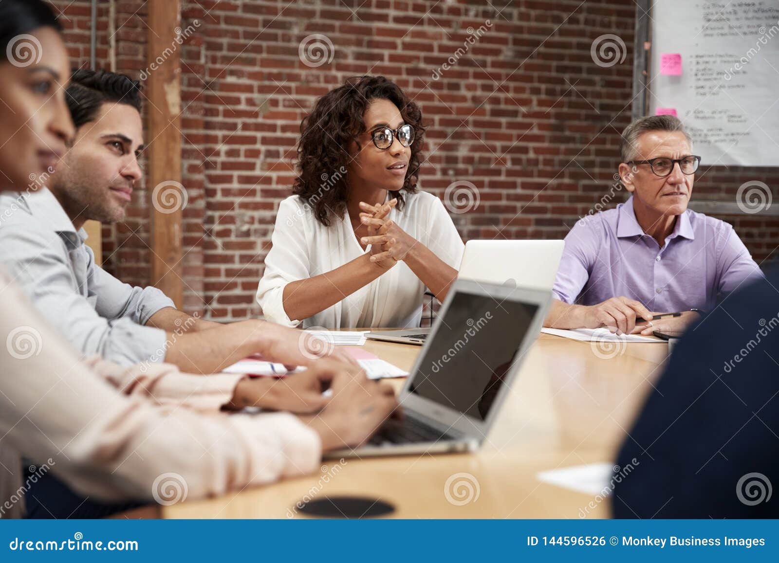 businesswoman leading office meeting of colleagues sitting around table