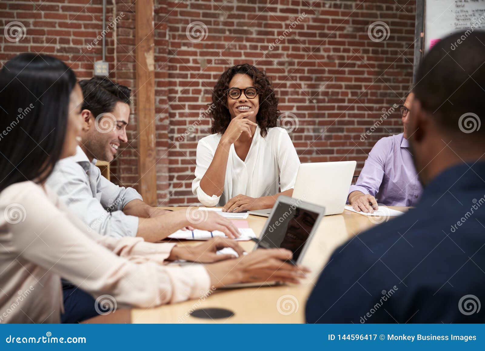 businesswoman leading office meeting of colleagues sitting around table