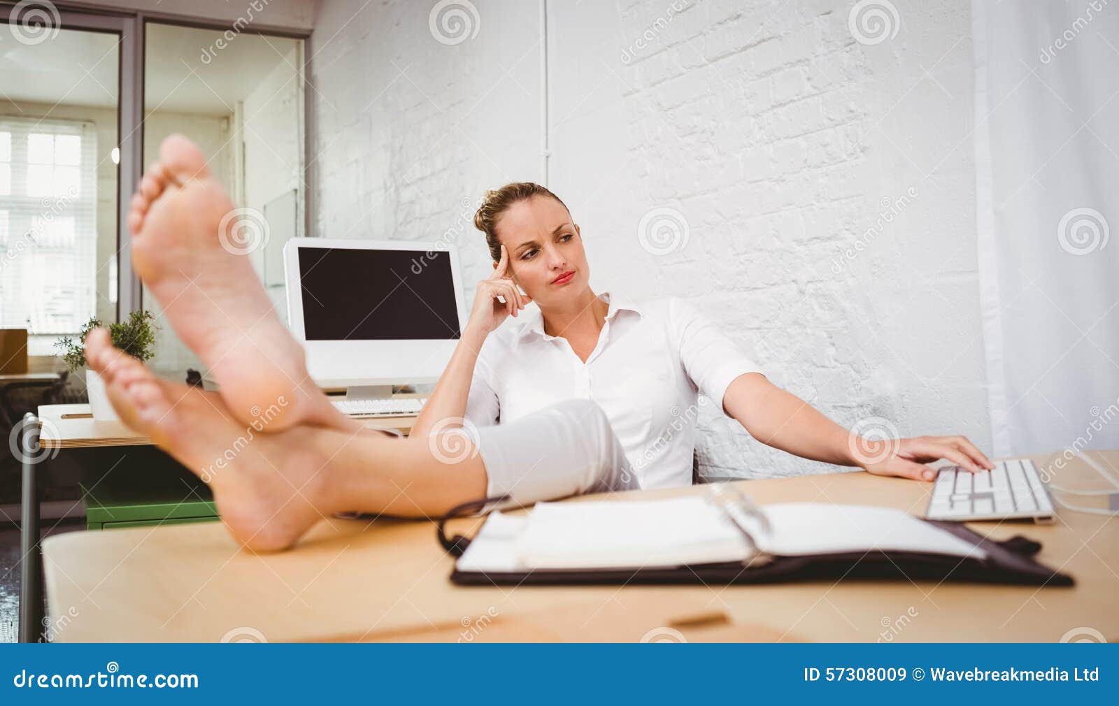 businesswoman legs crossed ankle desk relaxed young sitting office 57308009