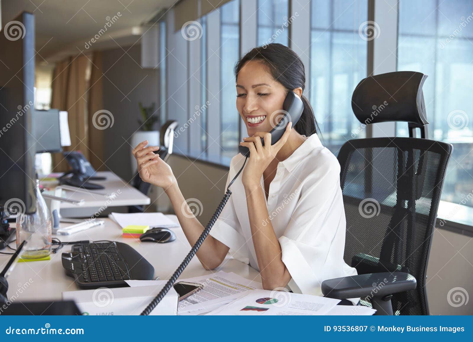 businesswoman making phone call sitting at desk in office