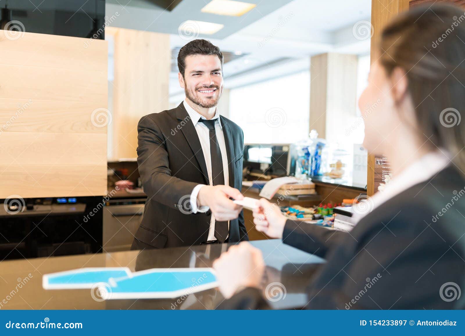 Businesswoman Paying Through Card At Front Desk In Hotel Stock