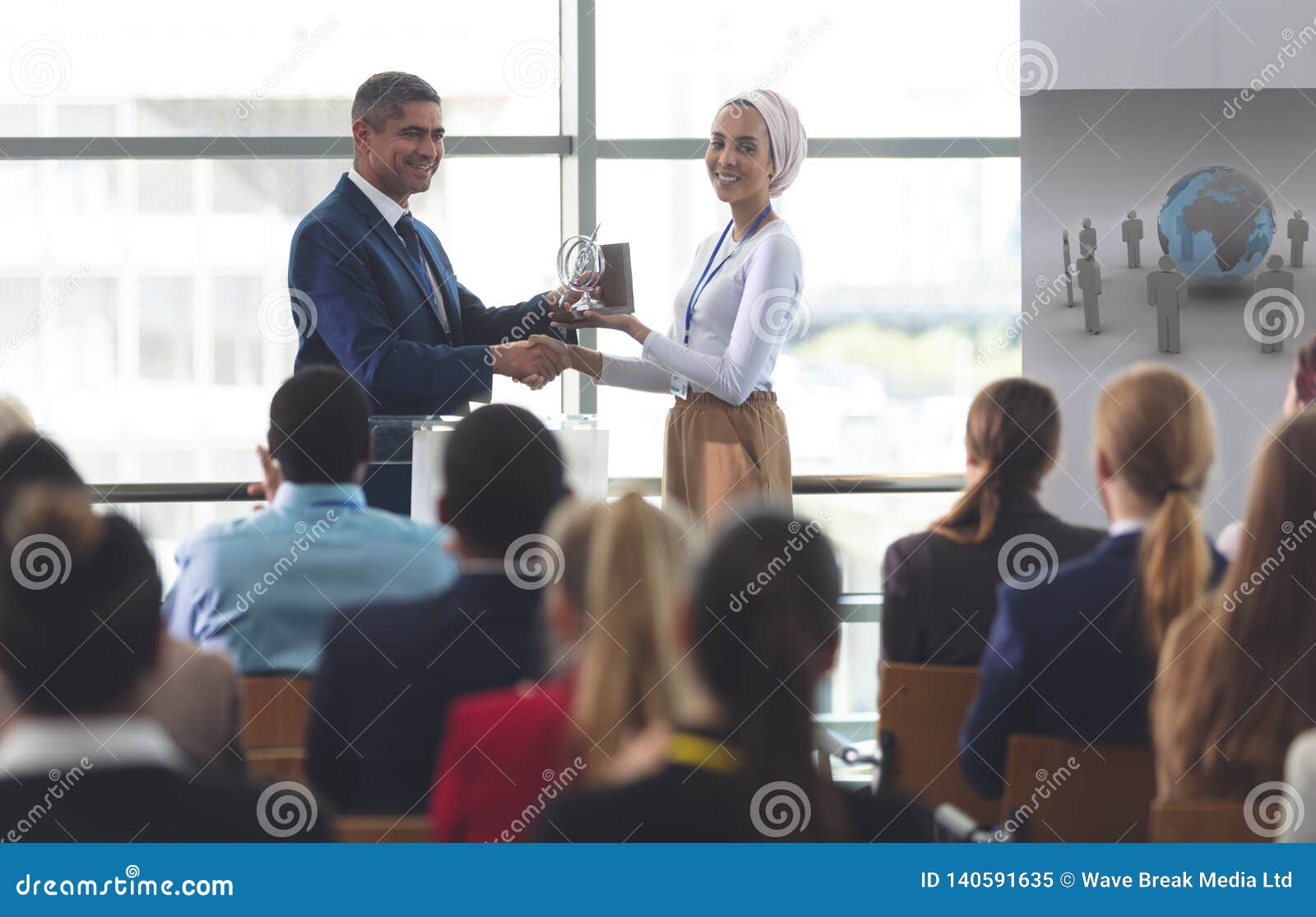 businesswoman receiving award from businessman in a business seminar