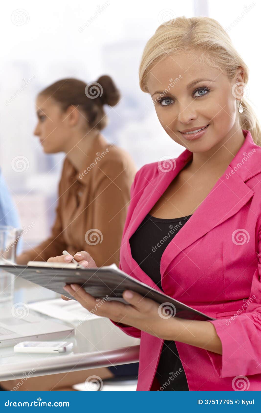 Businesswoman writing notes at meeting. Businesswoman writing notes at businessmeeting, smiling.