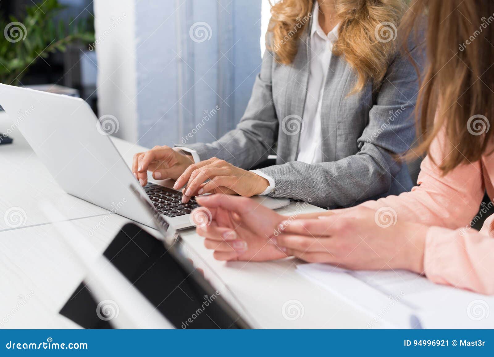 businesswomen use laptop computer typing on keyboard, teamwork concept, open space office two business women working on