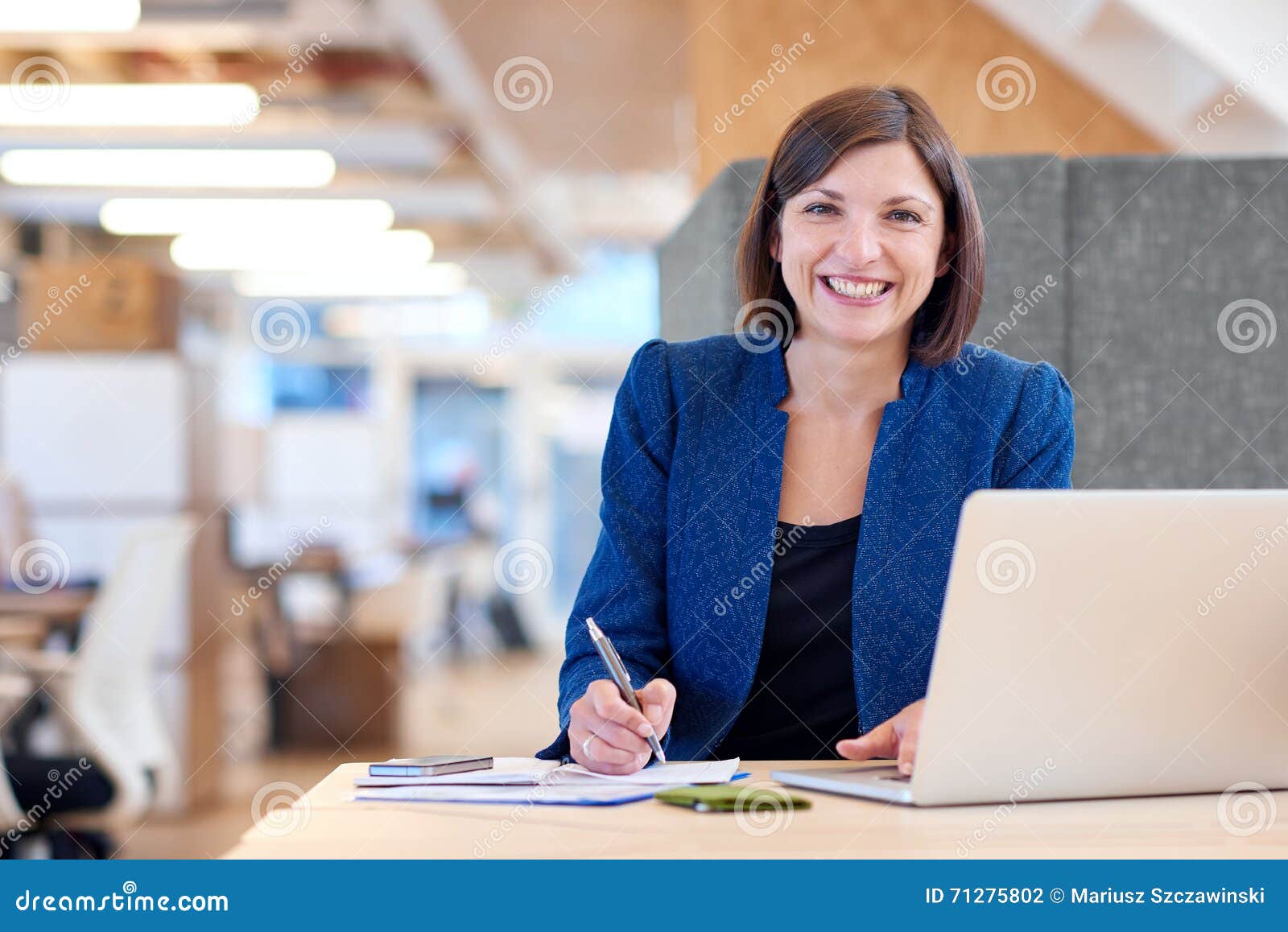 busineswoman smiling broadly while working in her office cubicle