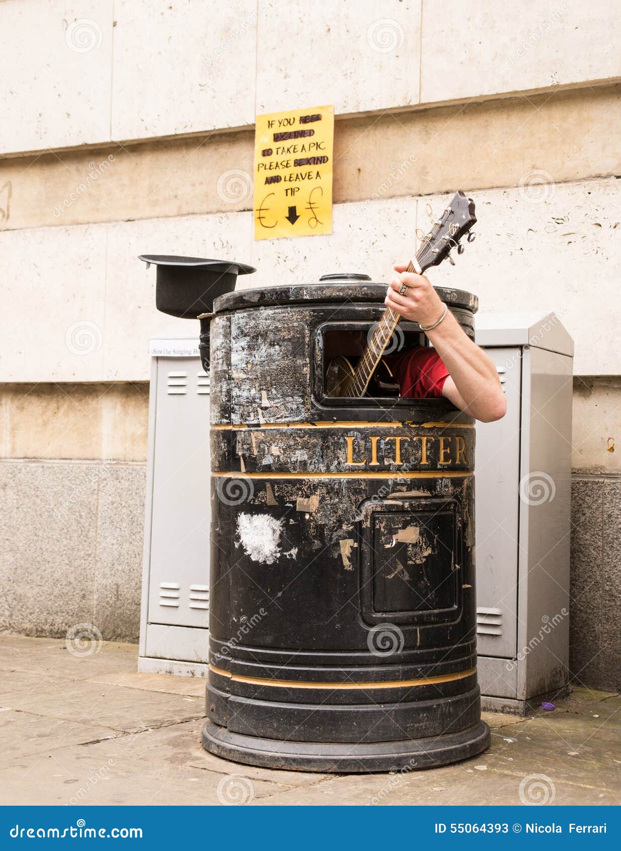 busker singing and playing guitar inside a rubbish bin