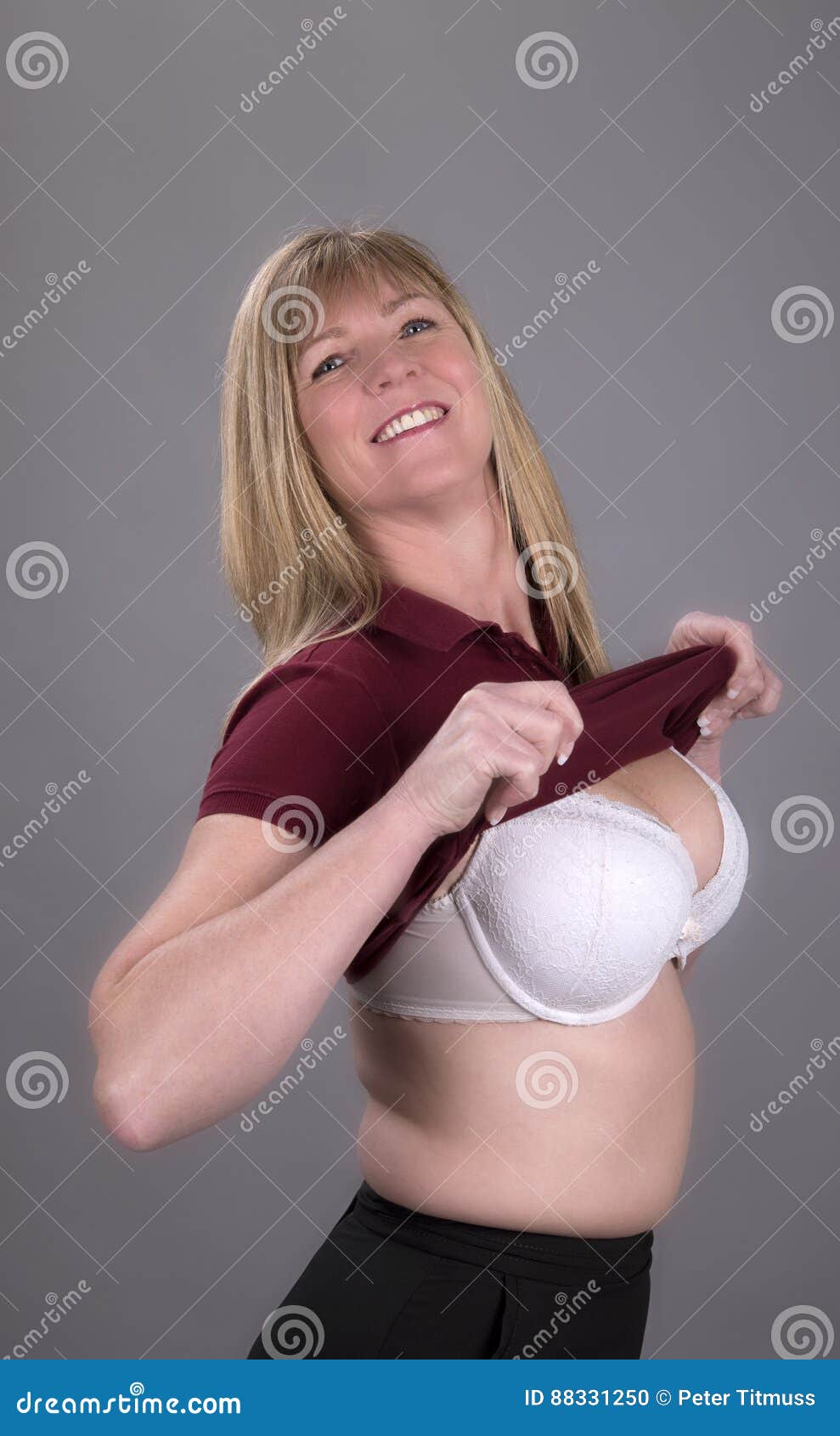 Busty Blond Woman Pulling Tight Shirt Over Her Boobs Stock Photo