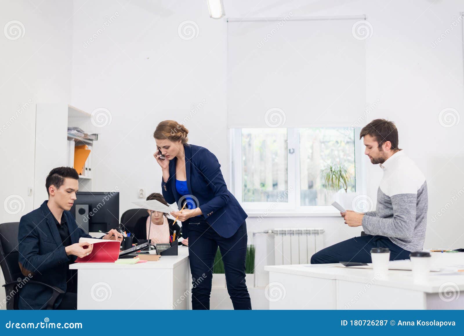 A Busy Work Day in the Modern Office. Four People Working in the Office
