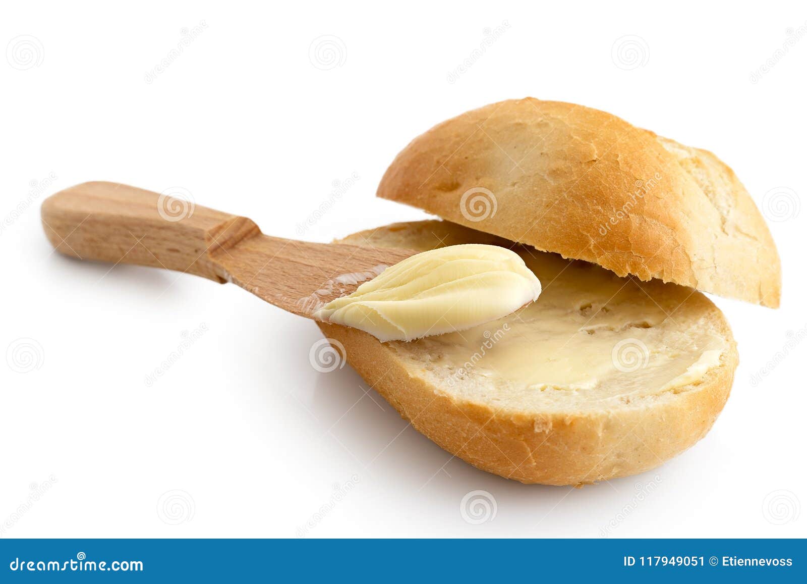 butter spread on a cut crusty bread roll with a wooden knife iso