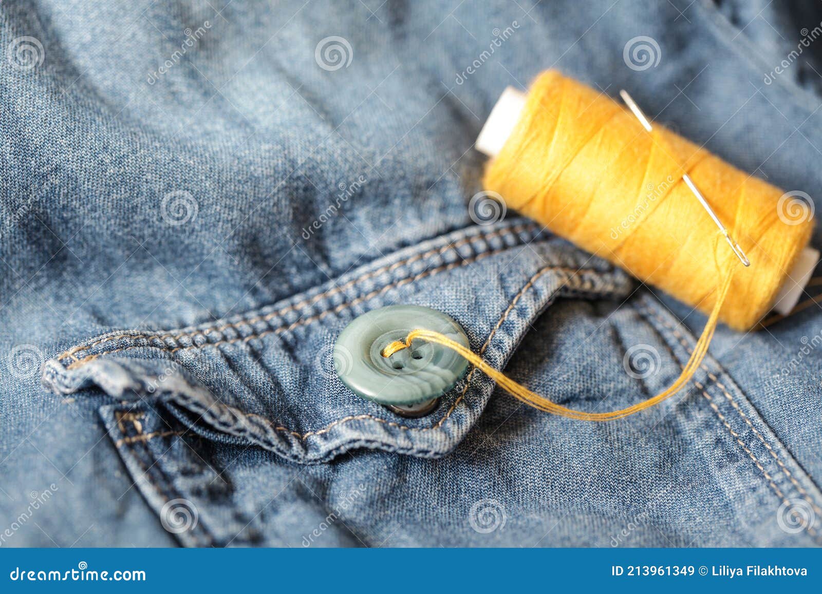 Buttons, Thread and Sewing Needle on Denim. Closeup Stock Image