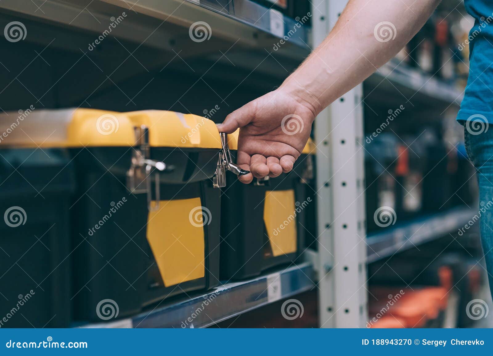 The Buyer in the Hardware Store Selects the Goods. a Man Holds a Tool
