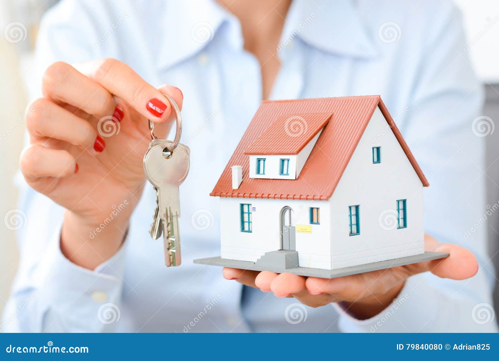 buying a house concept with woman hands holding a model house and keys